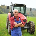 Proud farmer standing in front of his red tractor
